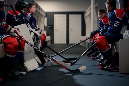 Free Hockey players in gear preparing for a game in the locker room showcasing teamwork and anticipation. Stock Photo