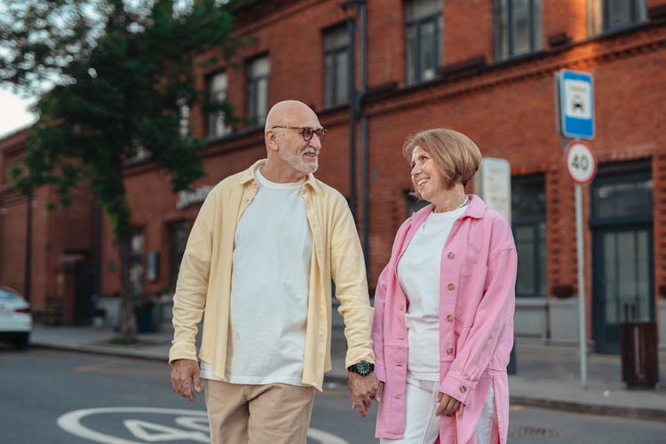 Happy Elderly Couple Holding Hands While Walking On The Street