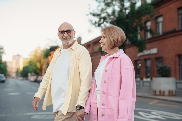 Happy Elderly Couple Holding Hands While Walking On The Street