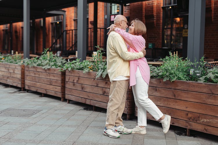 An Elderly Couple Hugging O The Street