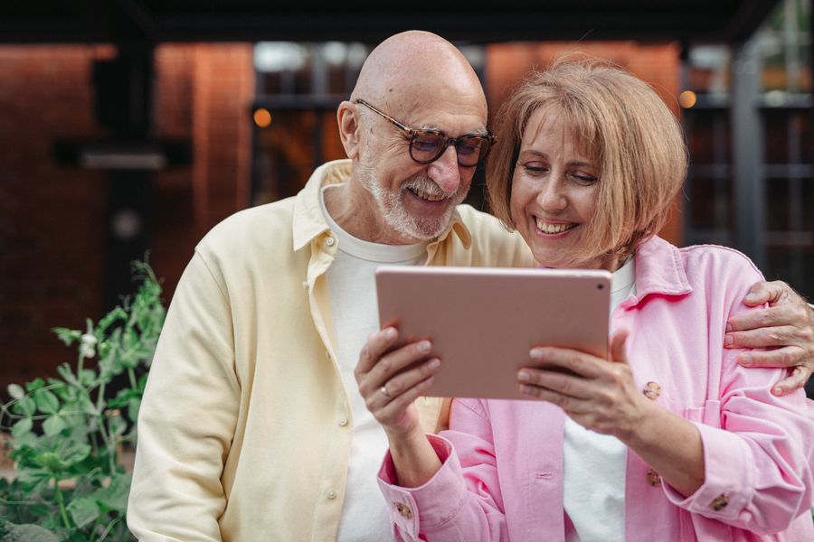Senior couple smiling while using a tablet together