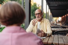 Elderly couple conversing at an outdoor cafe, enjoying a peaceful moment together.