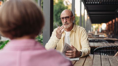 Elderly couple conversing at an outdoor cafe, enjoying a peaceful moment together.