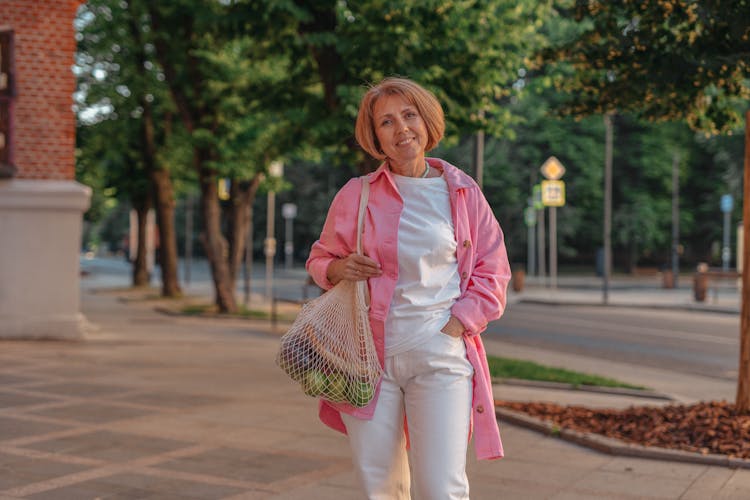 A Woman Carrying A Mesh Bag With Groceries