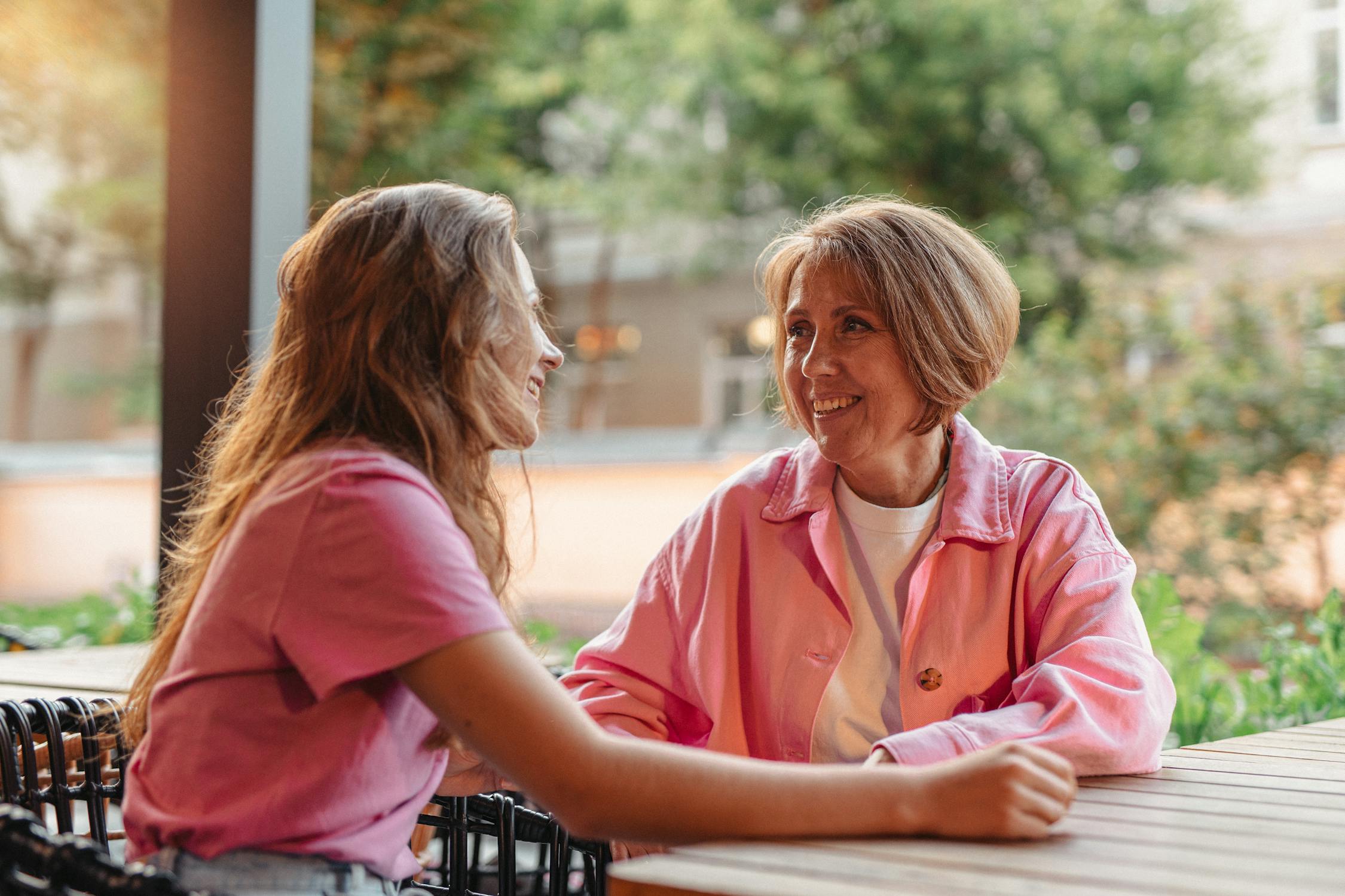 Woman in Pink Long Sleeve Polo Shirt Sitting Beside Woman in Pink Shirt