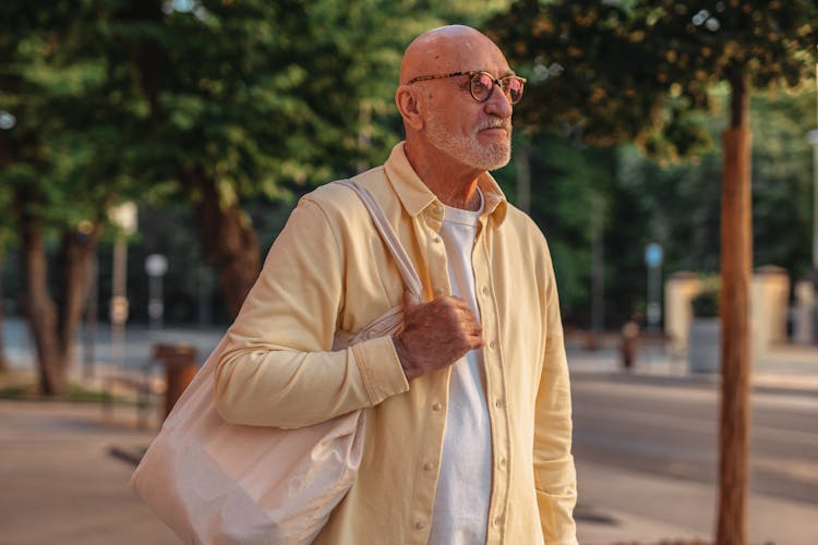 An Elderly Man Carrying A Cloth Bag