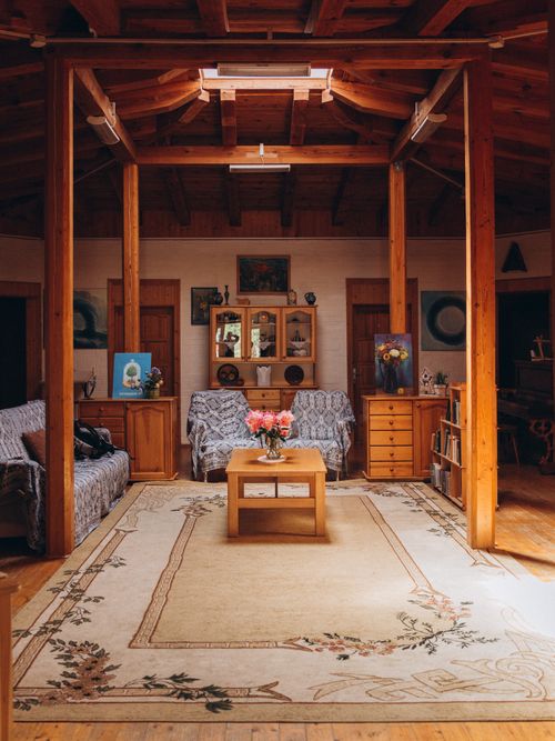 Free Warm rustic living room featuring wooden beams and floral carpet for a cozy ambiance. Stock Photo