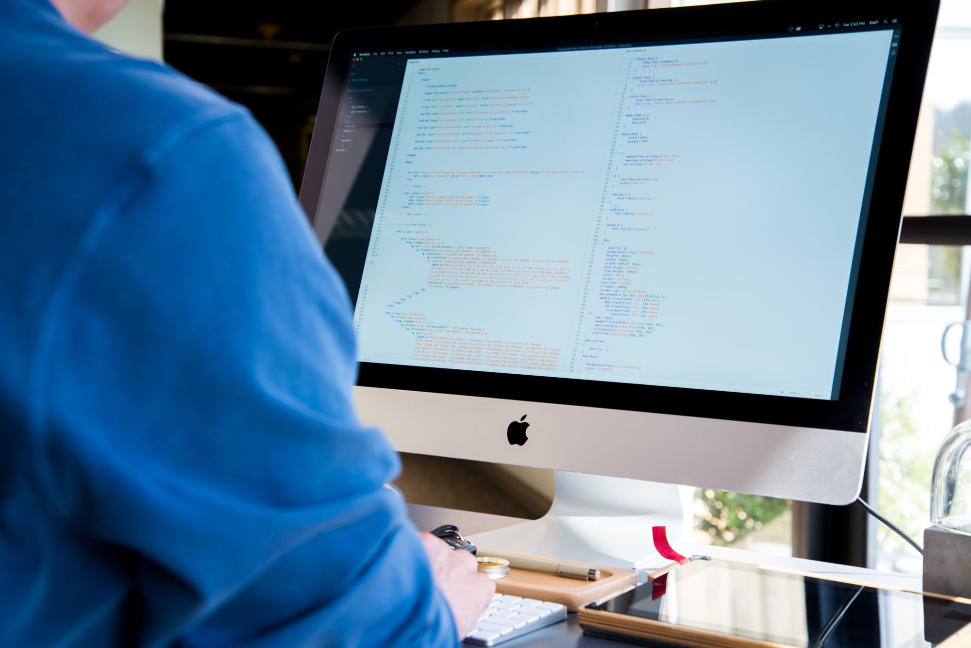 Persona programando frente a la pantalla de una computadora con líneas de código