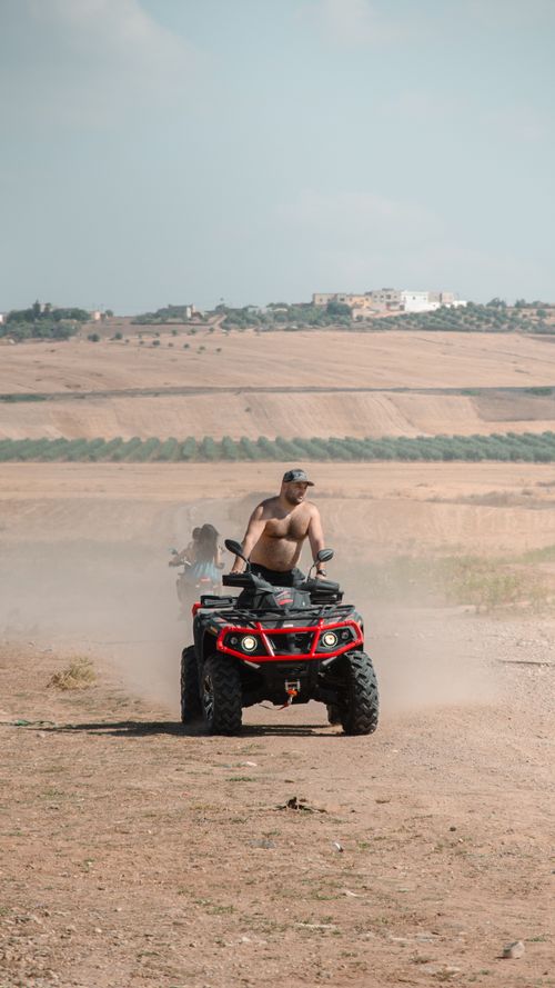 Free Man riding ATV through the dusty Moroccan desert under clear skies Stock Photo