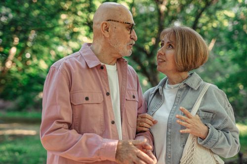 Senior couple chatting happily in a green park, a relaxed way to meet someone from an online conversation