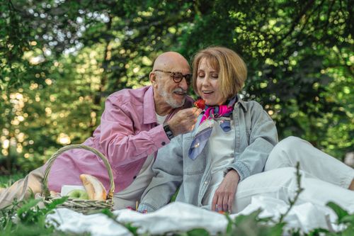 Free Elderly couple sharing a tender moment during a picnic in a lush green park. Stock Photo