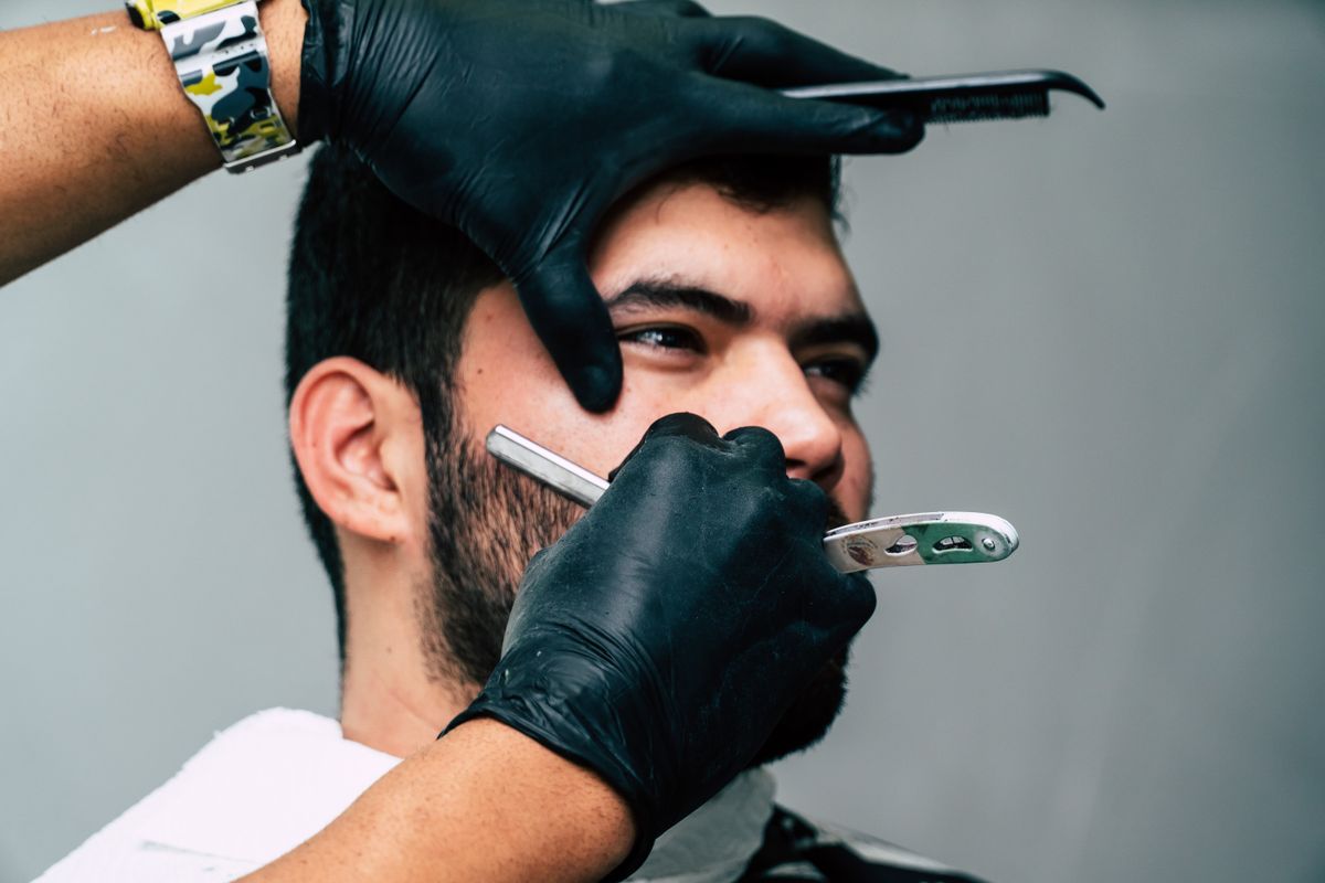Barber giving a client a straight razor shave at Ross' Times Barber Shop