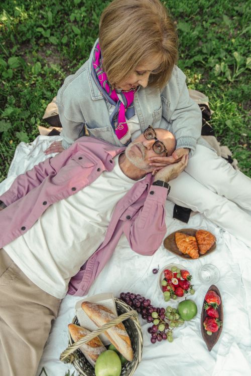 Free A senior couple shares a loving moment during a picnic with fruits and pastries. Stock Photo