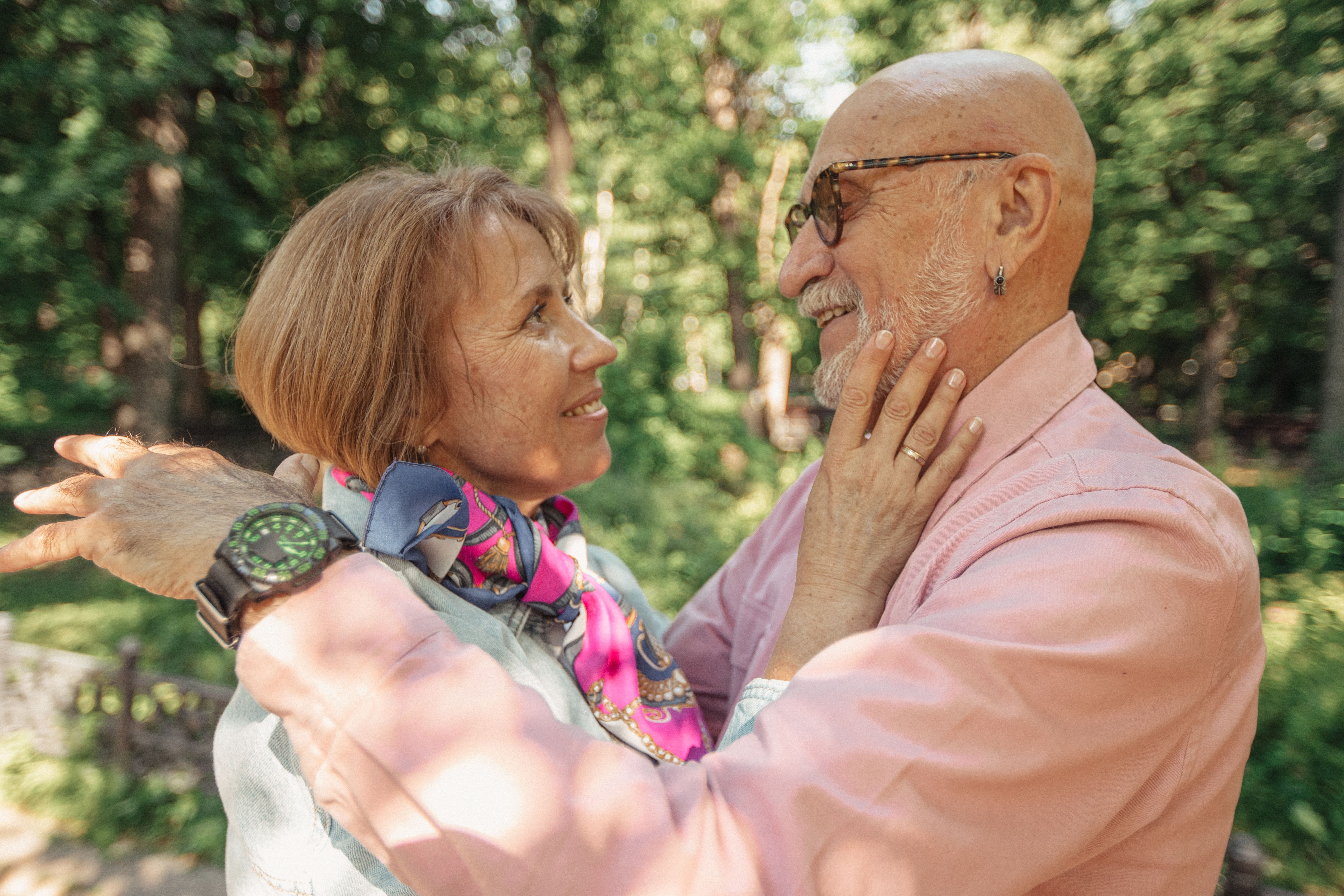 A senior couple shares a loving embrace in a sunlit park, symbolizing togetherness and joy.