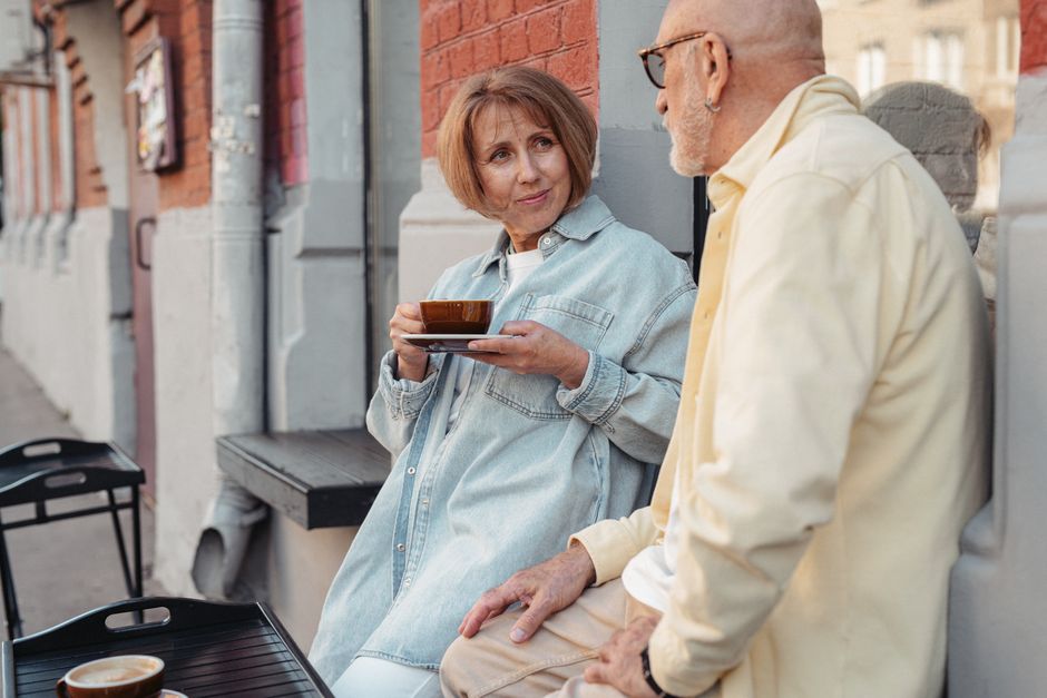 Senior couple enjoying coffee while sitting outdoors on a sunny day.