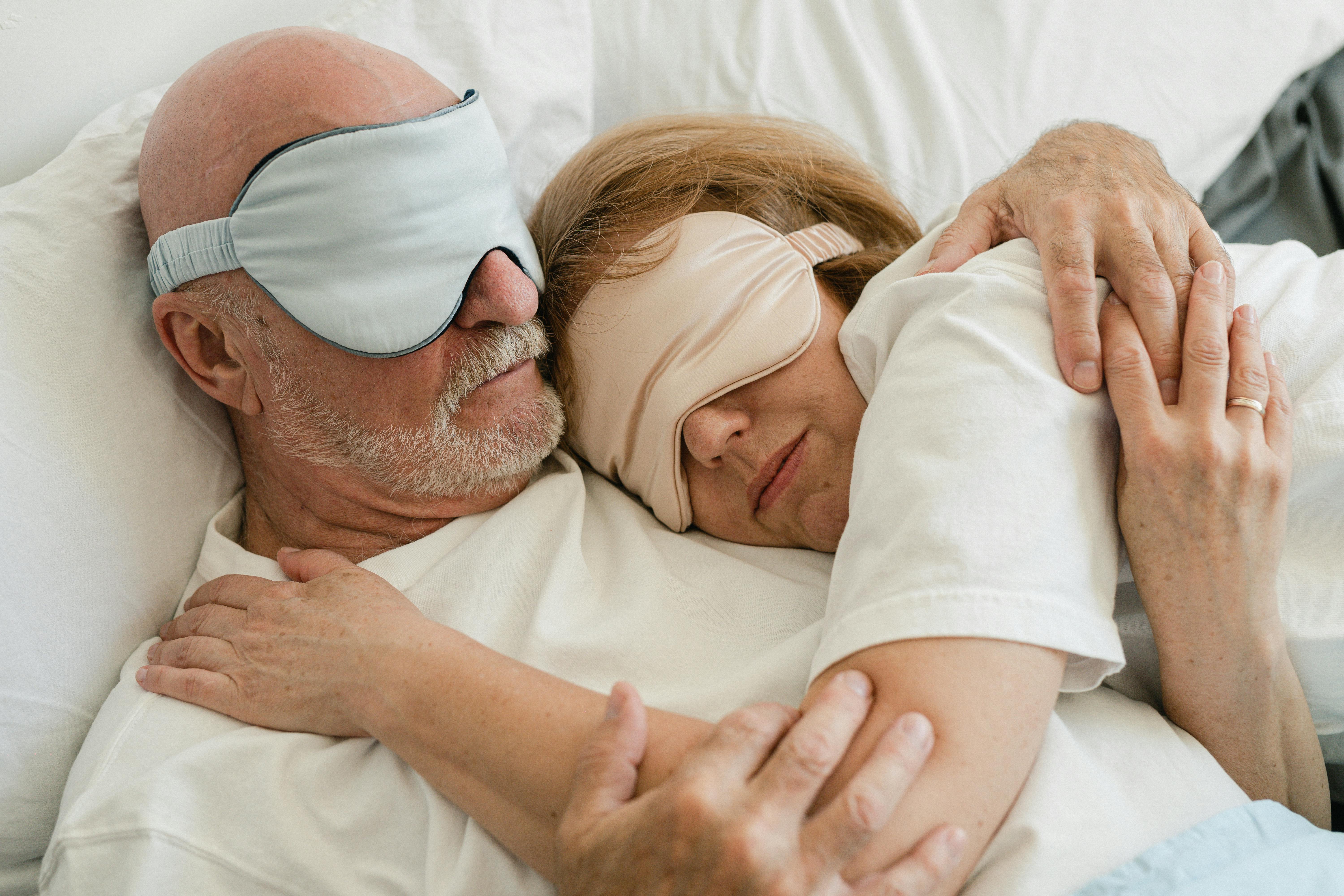 man and woman lying on bed with eye mask