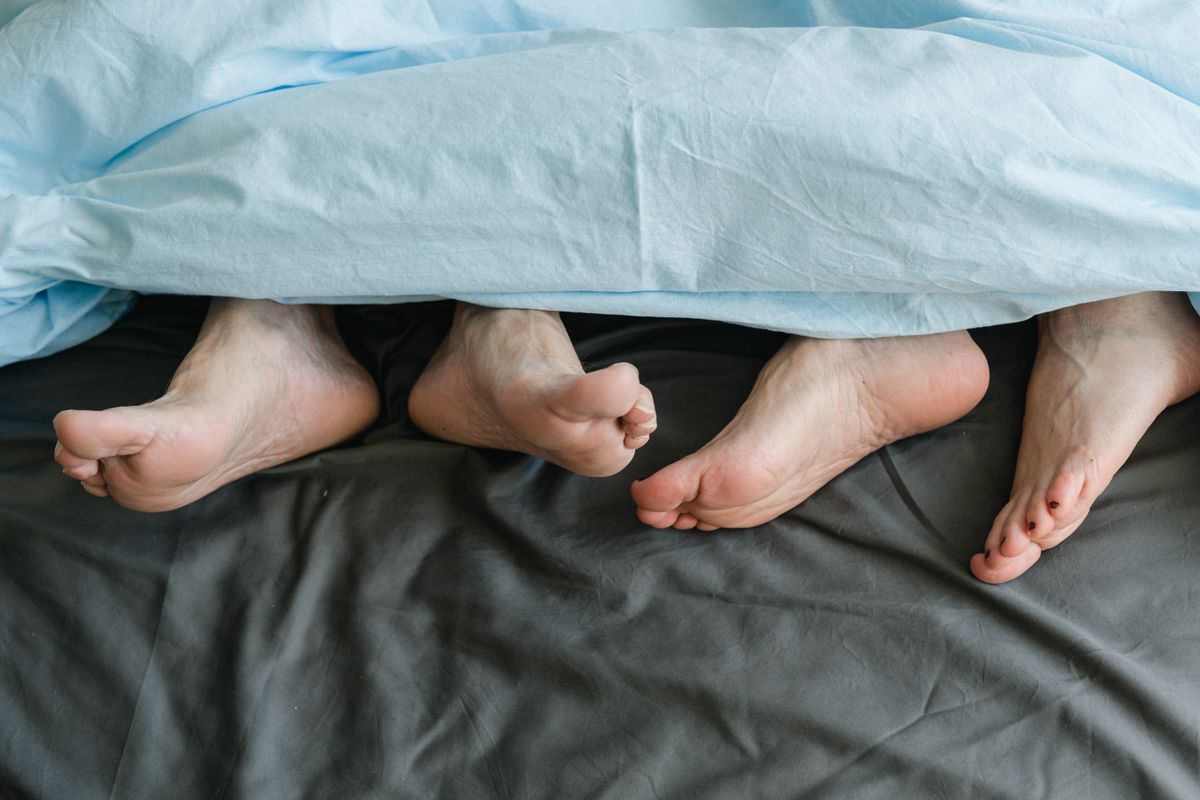 Pés sob uma coberta em uma cama