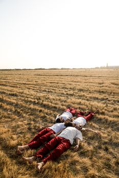 Three men in casual wear lying in a sunlit wheat field, capturing tranquility and nature's beauty.
