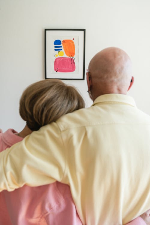 A Lovely Couple Hugging Each Other While Looking At A Picture Frame