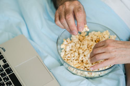 Close Up Photo of People Holding Popcorn