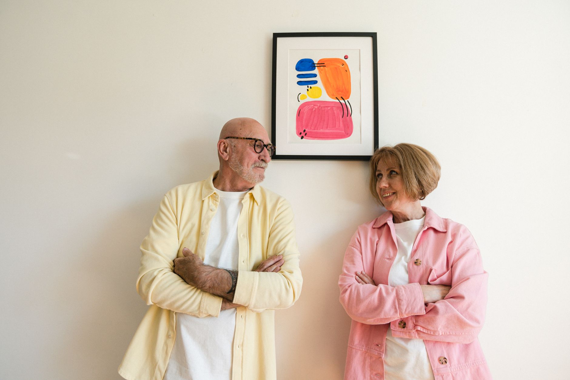 Quercetin anti aging — Elderly couple stands smiling at each other under vibrant artwork on a plain wall indoors.