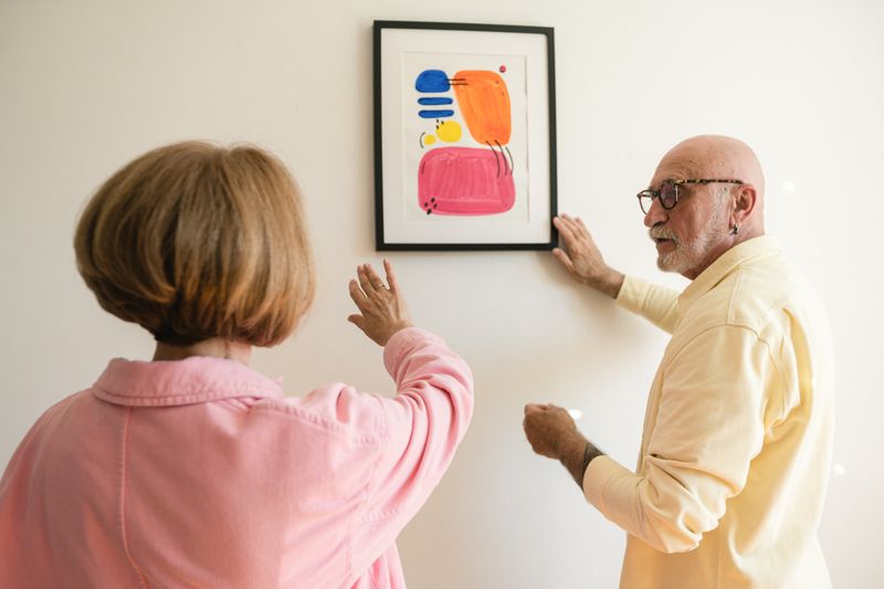 Casal posicionando quadro emoldurado em parede clara