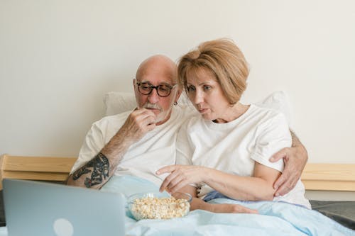 A Couple Eating Popcorn on the Bed
