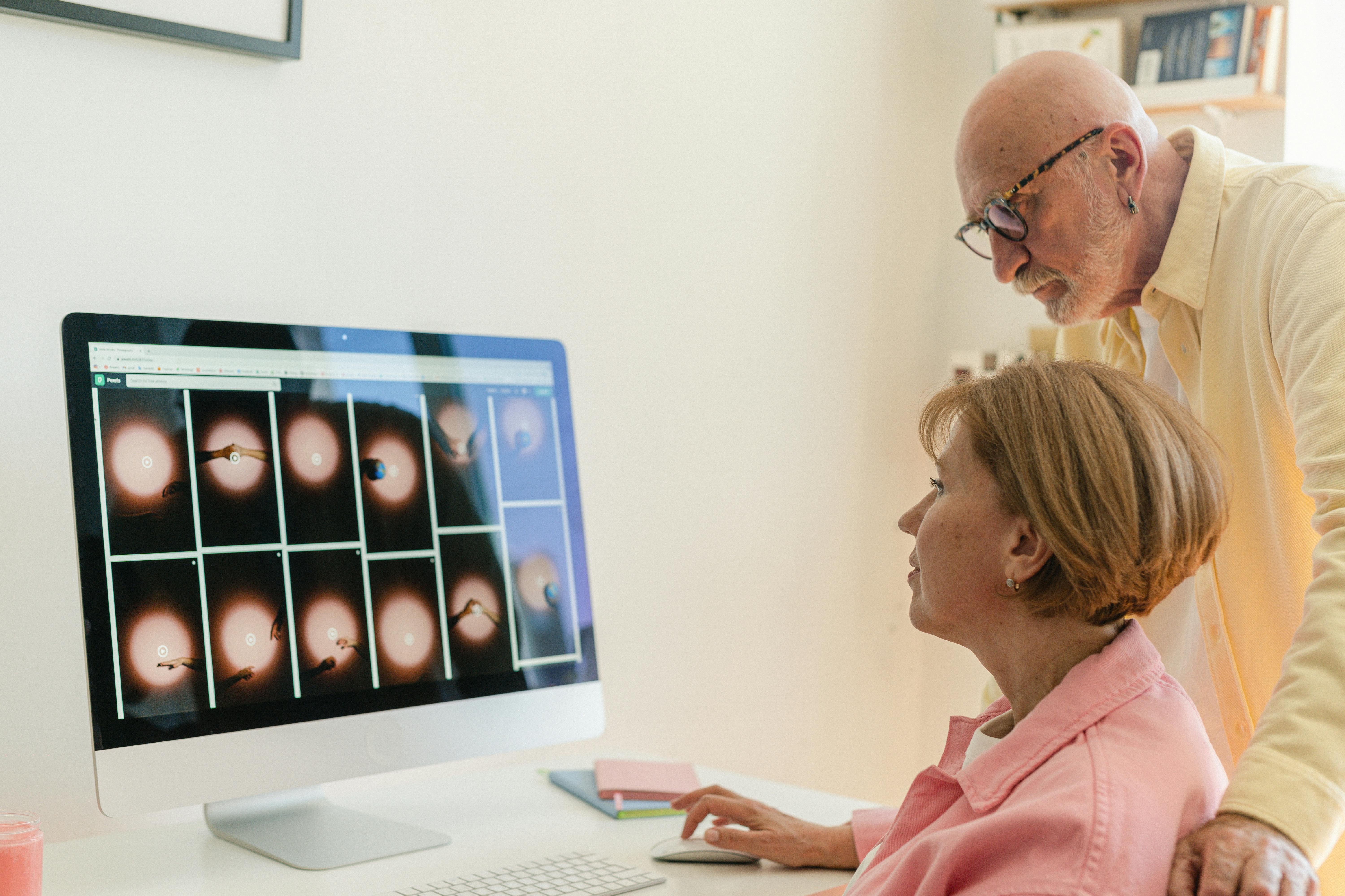 an elderly couple looking at the computer screen together