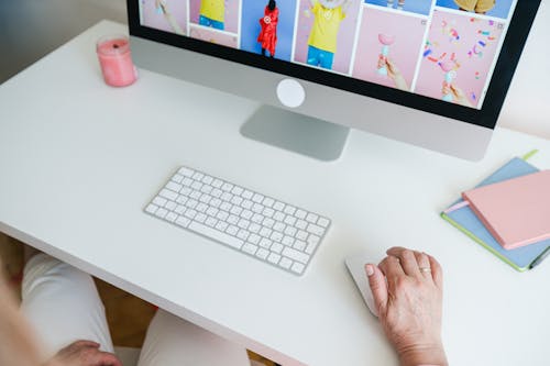 Person Using a Desktop Computer on a White Desk