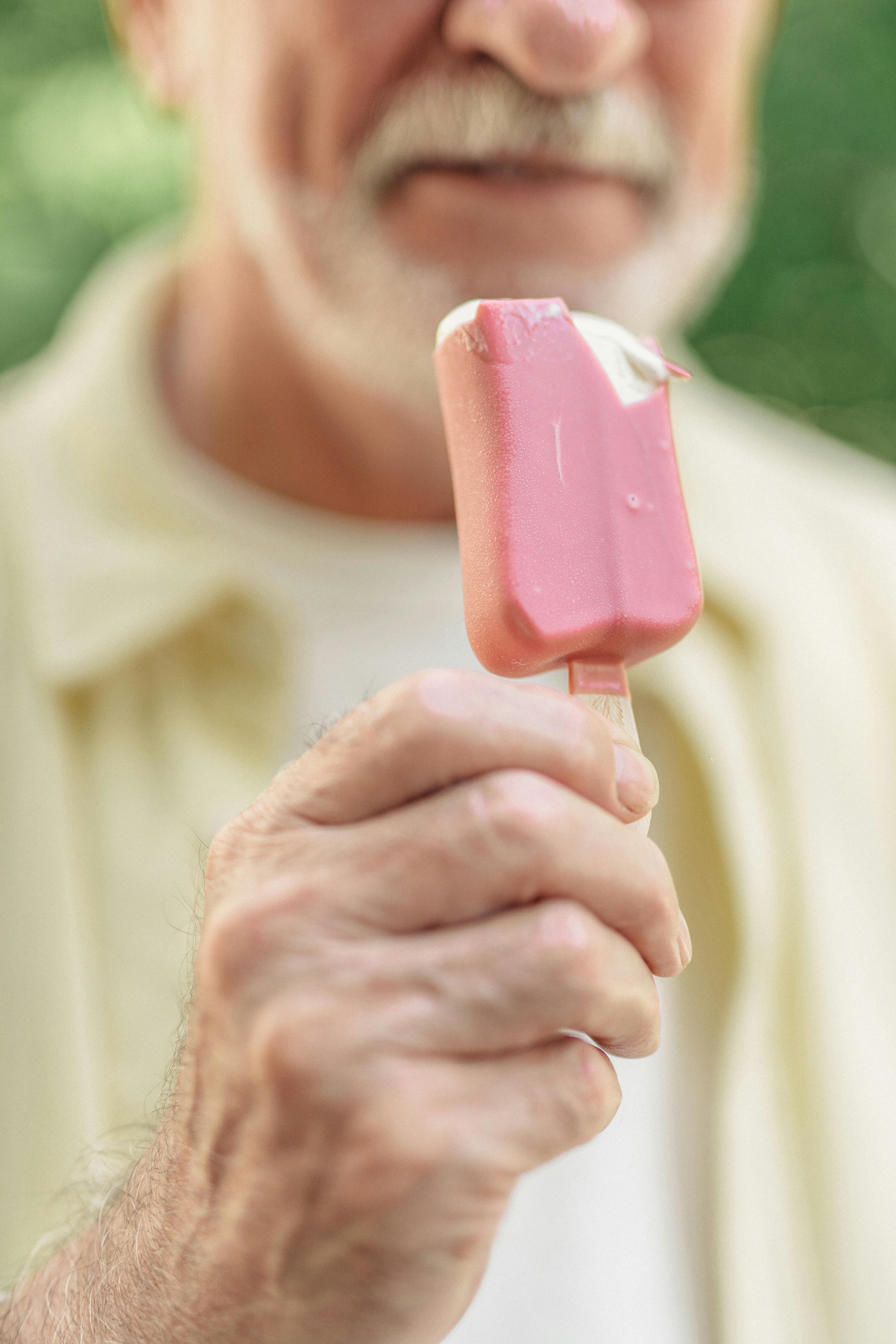 close up shot of an elderly man holding an ice pop