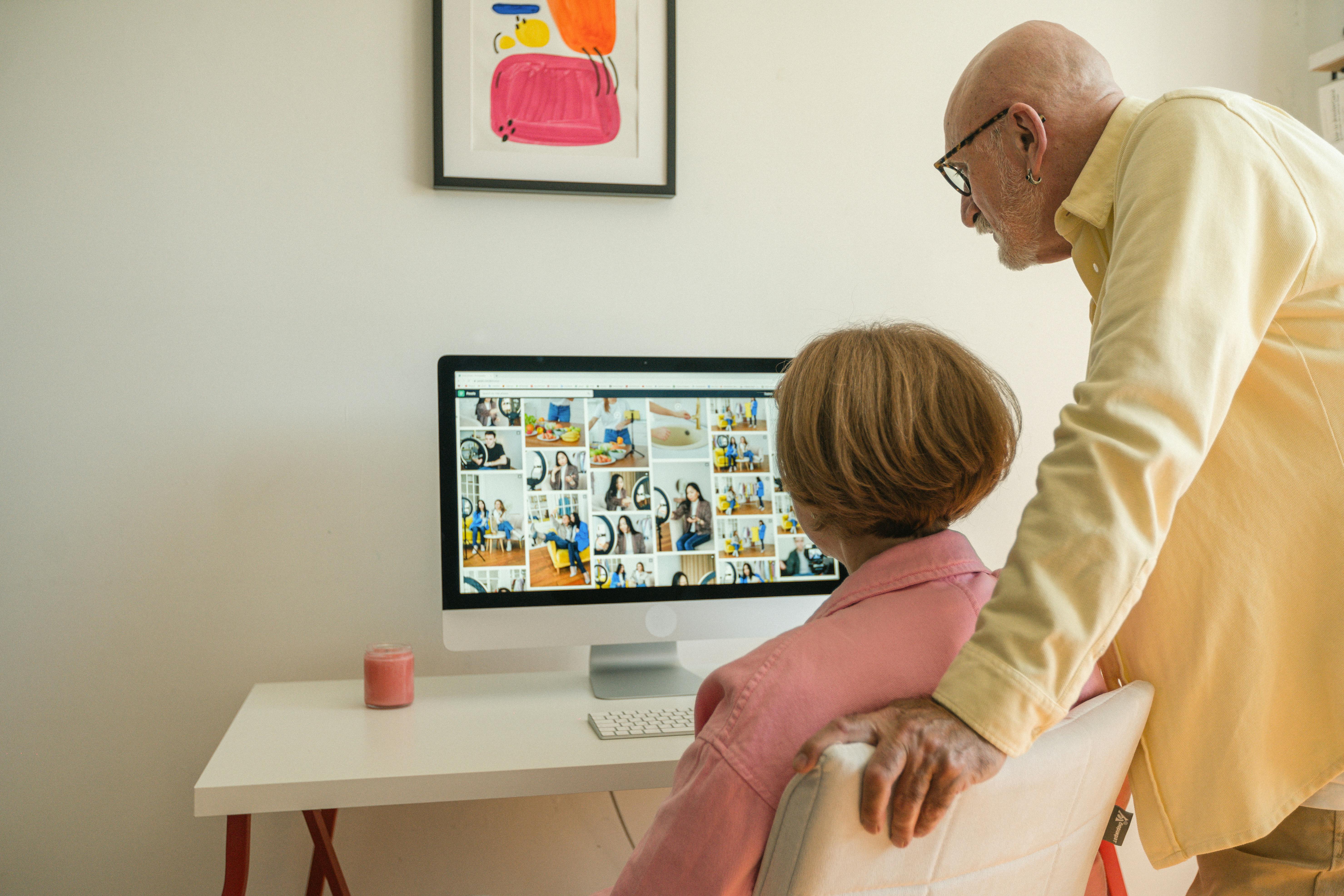 an elderly couple looking at pictures in a computer