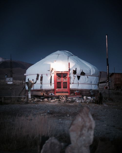 Bird flying over sandy terrain and yurt under blue sky · Free Stock Photo