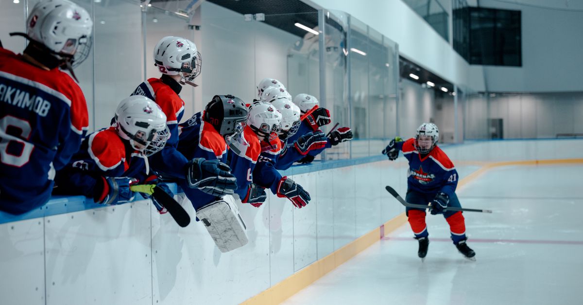 Youth hockey players energetically engaging in a game on an indoor ice rink.