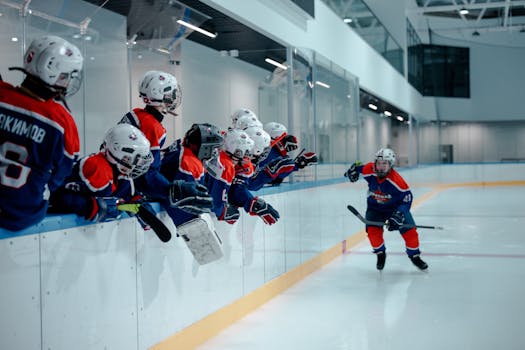 Youth hockey players energetically engaging in a game on an indoor ice rink.