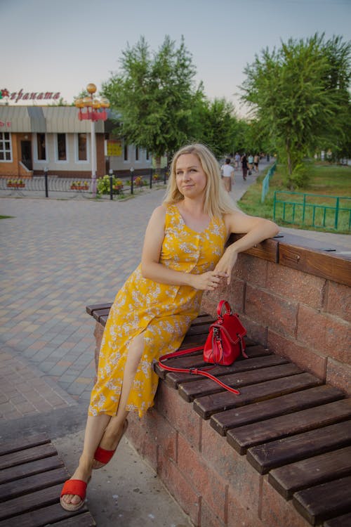 Blonde Woman Sitting on a Bench in a Yellow Dress 