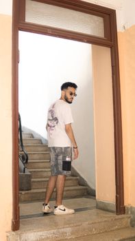 Stylish man wearing casual clothing stands in a doorway in Fes, Morocco.