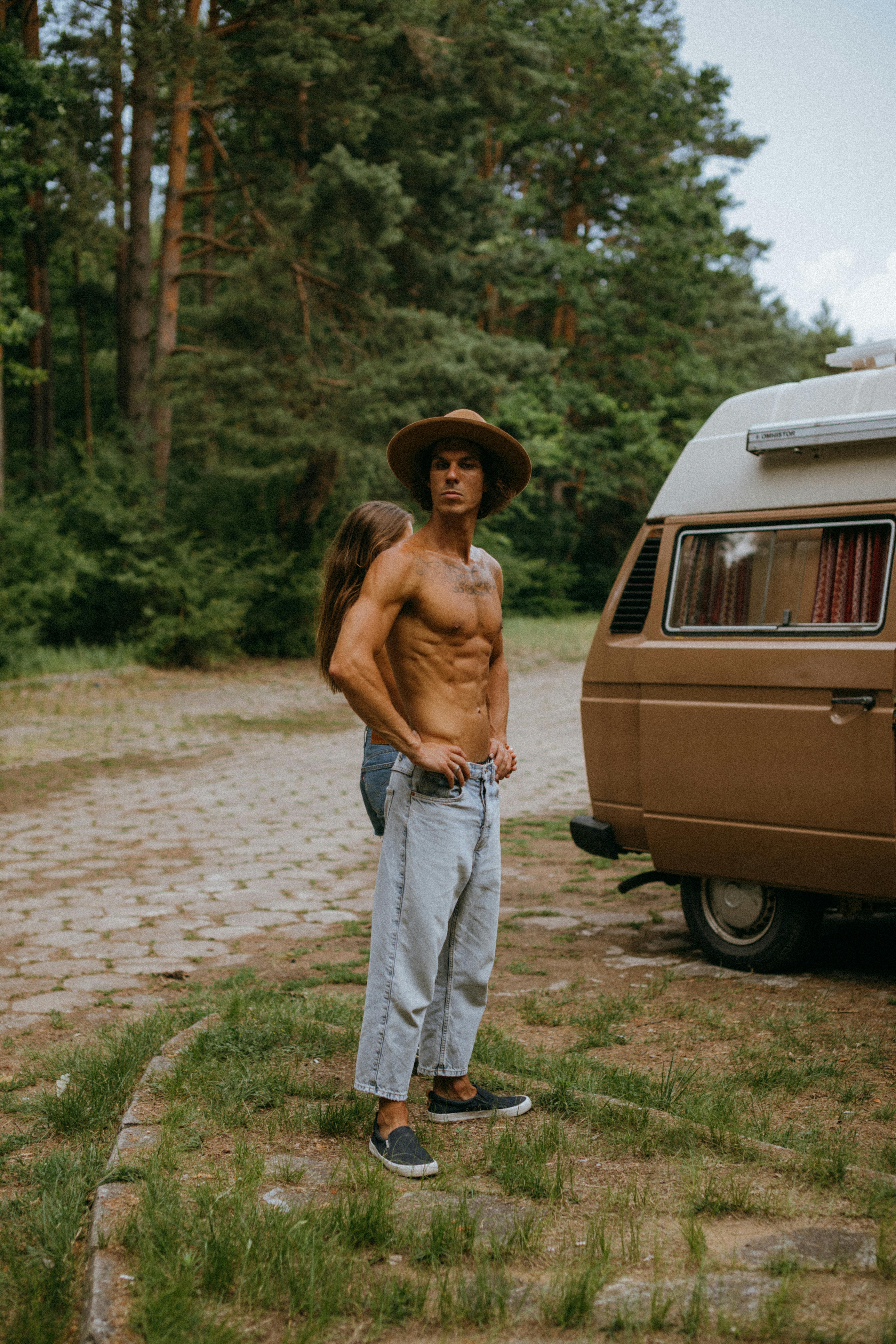 woman in blue denim jeans standing beside brown van