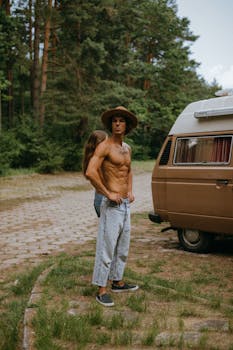 A young couple standing by a camper van, embracing the freedom of van life in a forest setting.