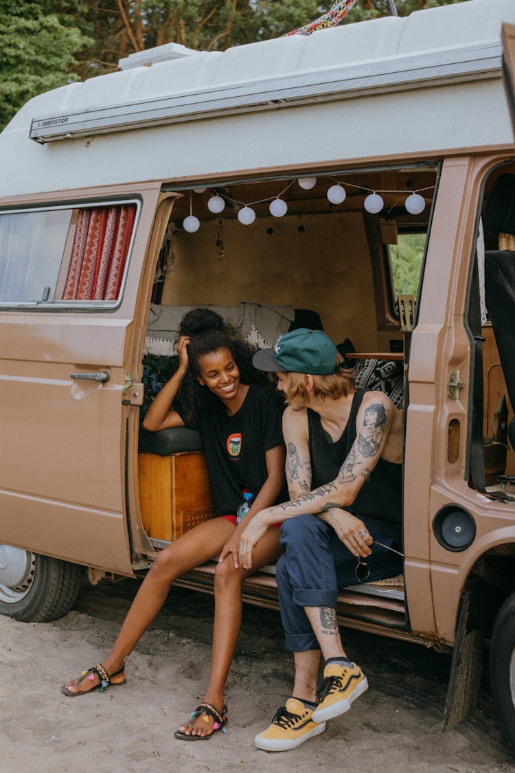 Woman In Black Shirt And Red Shorts Sitting On Brown Van