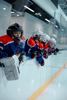 Young ice hockey players leaning over the rink boards during a game, showcasing teamwork and energy.