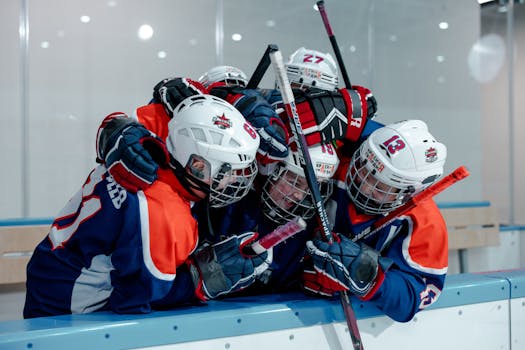 Group of young ice hockey players celebrating with an embrace on the ice rink.