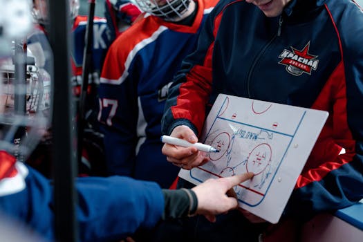 Hockey coach discussing tactics on a board with players during match break.