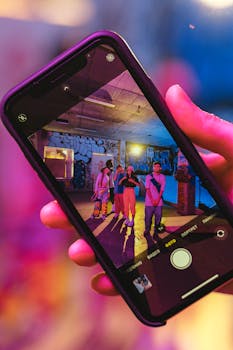 Close-up of a smartphone displaying a vibrant urban dance group in a graffiti-styled indoor setting.