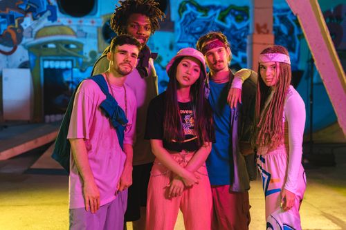Free Group of fashionable young adults in a colorful skatepark setting, showcasing trendy urban attire. Stock Photo
