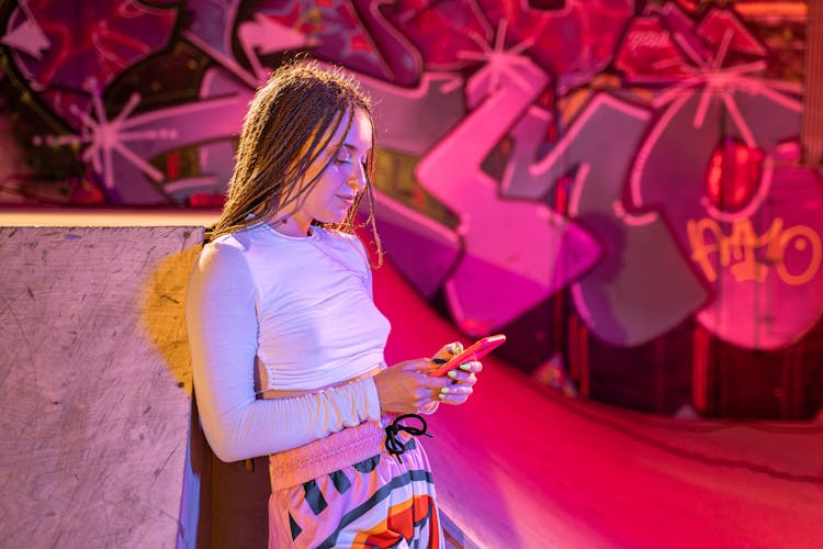 A Young Woman In A Stylish Outfit Using A Cellphone