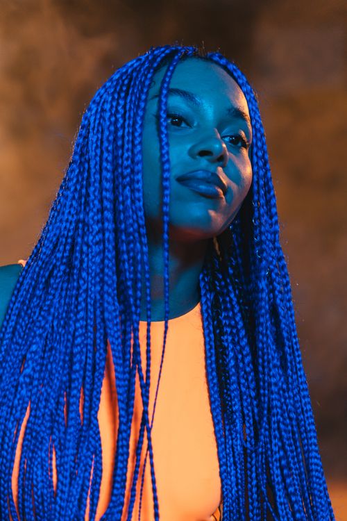 Free A striking portrait of a woman with bold blue braids against a blurred background. Stock Photo