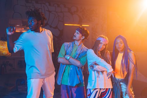 Free A lively group of young dancers in colorful street wear posing under bright lights during a public performance. Stock Photo