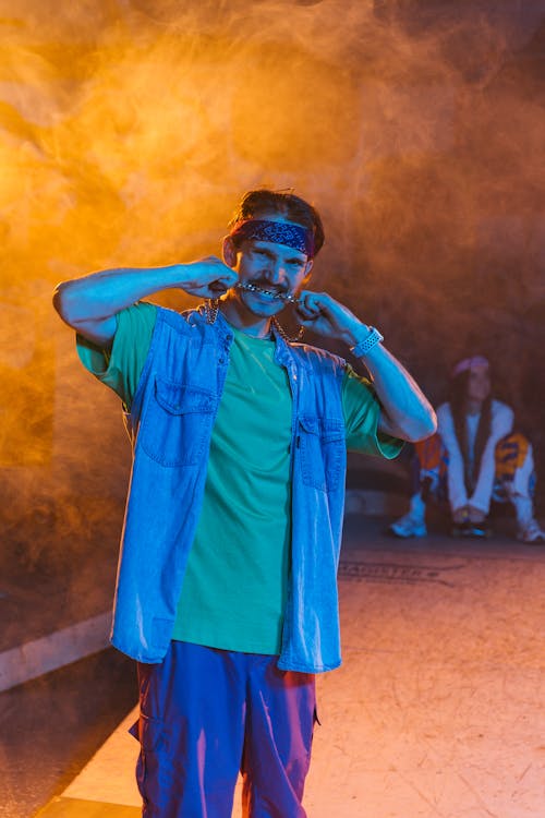 A Man Wearing Denim Shirt and Jeans Biting the Necklace