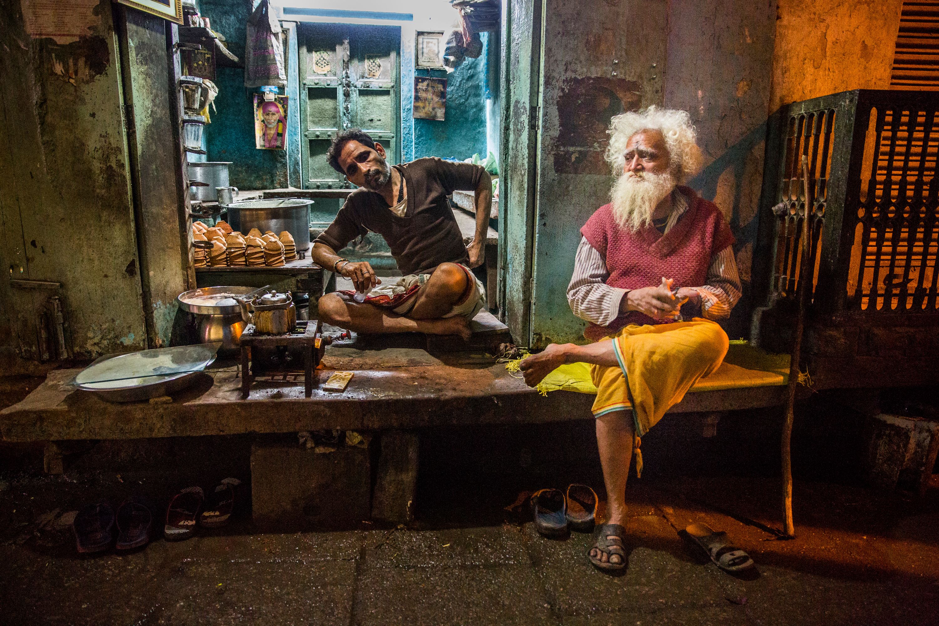 A traveler sitting at a small street food stall, laughing with an elderly local vendor, napkin with drawings visible