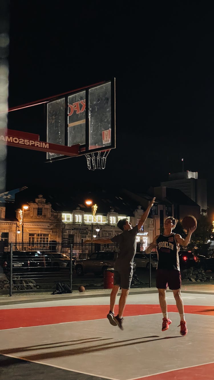 People Playing On Basketball Court During Night Time